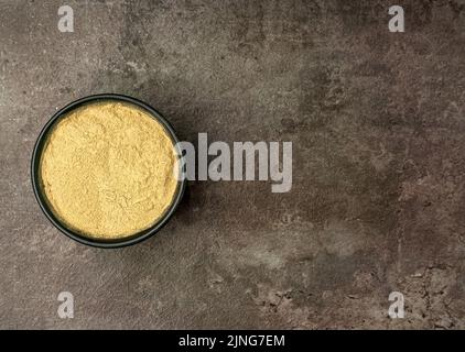 Aromatisches Ingwer-Pulver aus einem flachen Lay-Winkel mit einem dramatisch dunklen Hintergrund. Stockfoto