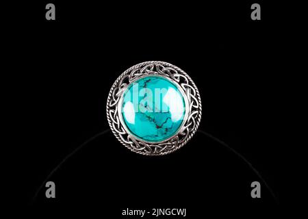 Silberner Ring mit türkisfarbenem Stein auf schwarzem Hintergrund Stockfoto