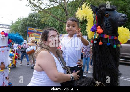 Eine Verkäuferin und ihr Sohn an einem Stand mit einer hölzernen Tierstatue. Bei der ecuadorianischen Parade NYC 2022 in Jackson Heights, Queens, New York City. Stockfoto