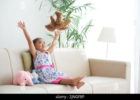 Schönes kleines Mädchen, das ihren Teddybär wirft Stockfoto