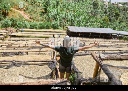 Junger Mann, der an den Seiten der Kaffeestation in Afrika die Hände hält Stockfoto