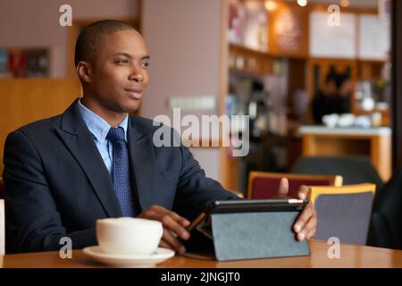 Porträt eines lächelnden, gutaussehenden Geschäftsmannes mit Tablet-Computer im Café Stockfoto