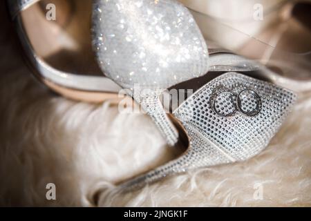 Zwei goldene Ringe liegen auf Hochzeitsschuhen. Stockfoto