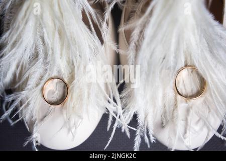 Zwei goldene Ringe liegen auf Hochzeitsschuhen. Stockfoto