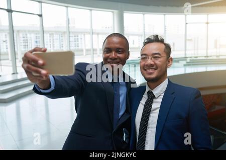 Happt multiethnische Geschäftspartner nehmen Selfie am Flughafen auf Stockfoto