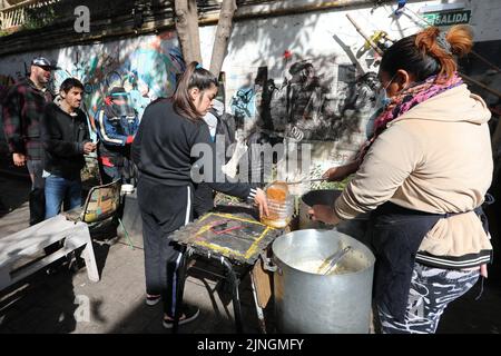 Buenos Aires, Argentinien. 10. August 2022. Eine Frau gießt Suppe für arme Menschen in einen auf Größe geschnittenen Wasserkanister. Im südamerikanischen Land ist die Inflationsrate weiter gestiegen. Kredit: Claudio Santisteban/dpa/Alamy Live Nachrichten Stockfoto