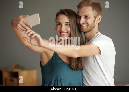 Porträt eines fröhlichen jungen Paares, das gemeinsam Selfie mit dem Smartphone nimmt Stockfoto