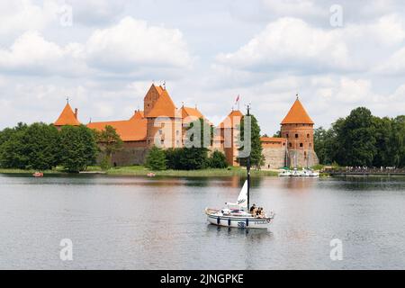 Litauen Reise; Ein Segelboot segelt auf dem Trakai See vor der restaurierten mittelalterlichen Burg Trakai im Sommer, Trakai, Litauen Europa Stockfoto