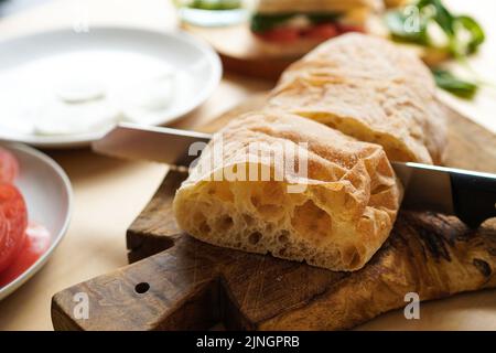 Brot am Tisch schneiden, um Sandwiches zu machen Stockfoto