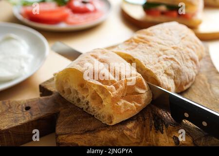 Brot am Tisch schneiden, um Sandwiches zu machen Stockfoto