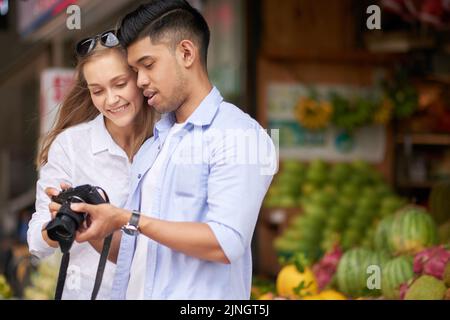 Gemischtes junges Paar Touristen, die Fotos vor der Kamera begutachten Stockfoto