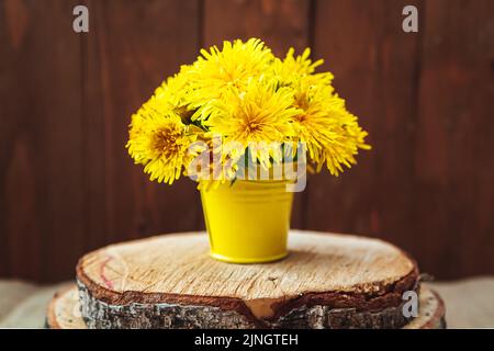 Bouquet von gelben Dandelionen in einem Eimer. Holzhintergrund. Grußkarte. Stockfoto
