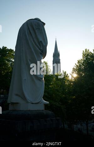 Sonnenuntergang in Sanctuaires Notre-Dame de Lourdes, einem katholischen Wallfahrtsort in Südfrankreich. Das Heiligtum unserer Lieben Frau von Lourdes. Kirche. Schreinstatue. Stockfoto