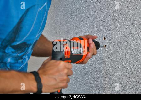 Zimmermann arbeitet sorgfältig, Mann bohrt eine Wand. Arbeiten zu Hause. Stockfoto