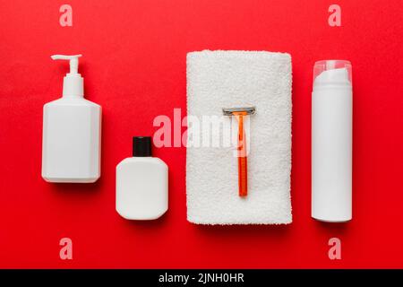 Rasierer-Set. Schermaschine, Handtuch, Lotion und Rasierschaum auf farbigem Hintergrund. Herren Bad Accessoires Draufsicht. Stockfoto