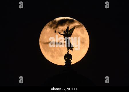 Dresden, Deutschland. 11. August 2022. Der Mond steigt am Abend hinter der Kuppel der Akademie der Schönen Künste mit dem Engel 'Fama' auf. Am 12. August 2022 wird der Vollmond wieder zum sogenannten Supermond. Kredit: Robert Michael/dpa/Alamy Live Nachrichten Stockfoto