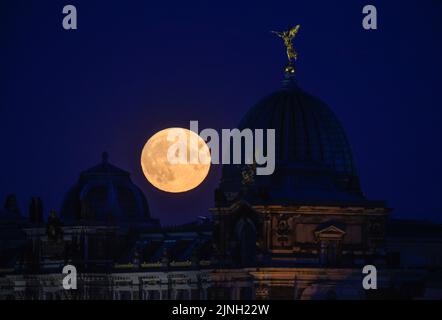 Dresden, Deutschland. 11. August 2022. Der Mond steigt am Abend hinter der Kuppel der Akademie der Schönen Künste mit dem Engel 'Fama' auf. Am 12. August 2022 wird der Vollmond wieder zum sogenannten Supermond. Kredit: Robert Michael/dpa/Alamy Live Nachrichten Stockfoto