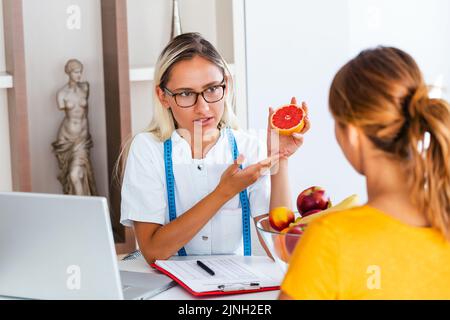 Porträt einer jungen lächelnden Ernährungsberaterin im Sprechzimmer. Machen Diät-Plan. Junge Frau besucht Ernährungsberaterin in Gewichtsverlust Klinik Stockfoto