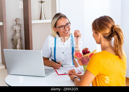 Porträt einer jungen lächelnden Ernährungsberaterin im Sprechzimmer. Machen Diät-Plan. Junge Frau besucht Ernährungsberaterin in Gewichtsverlust Klinik Stockfoto