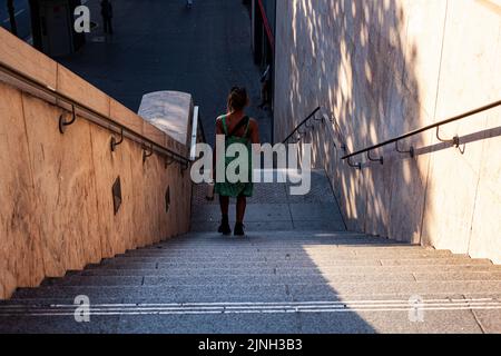 Rückansicht einer jungen Frau, die in Paris die Treppe hinunterkommt. Stadttourismuskonzept Stockfoto