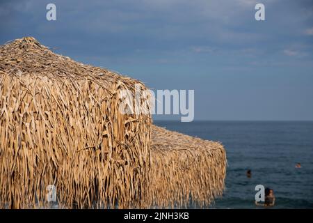 Sonnenschirm aus Palmenblättern am Strand. Tropischer Stil Stockfoto