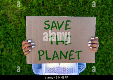 Aktivist mit dem Plakat „Rettet den Planeten“ zum Klimawandel Stockfoto