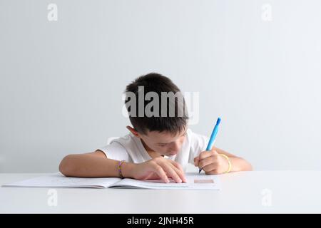 Kind, das zu Hause auf einem Schulbuch studiert. Die Konzentration der Kinder zu lernen Stockfoto