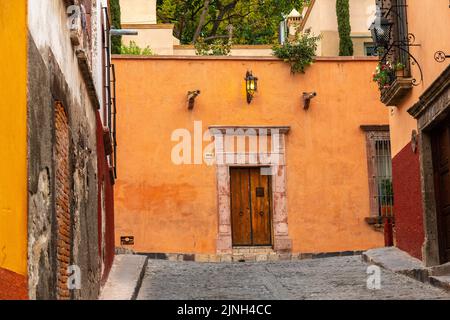 Eine Holztür im mexikanischen Stil und eine farbenfrohe Fassade an einem spanischen Kolonialhaus in der Calle Barranca im historischen Stadtzentrum von San Miguel de Allende, Mexiko. Stockfoto