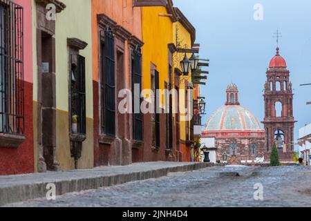 Die neoklassizistische Kuppel und der Glockenturm der Iglesia de San Francisco überragen die kopfsteingepflasterte Straße in der Calle Recreo im historischen Stadtzentrum von San Miguel de Allende, Mexiko. Stockfoto