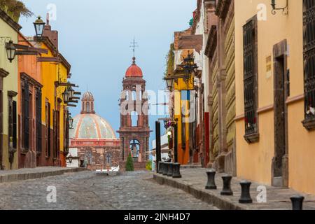 Die neoklassizistische Kuppel und der Glockenturm der Iglesia de San Francisco überragen die kopfsteingepflasterte Straße in der Calle Recreo im historischen Stadtzentrum von San Miguel de Allende, Mexiko. Stockfoto