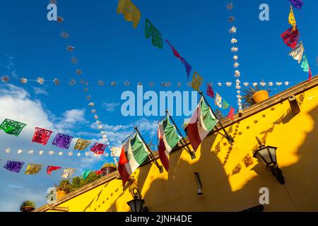 Farbenfrohe Papel-picado-Fiesta-Banner und mexikanische Flaggen schmücken ein Gebäude im spanischen Kolonialstil im historischen Stadtzentrum von San Miguel de Allende, Mexiko. Stockfoto