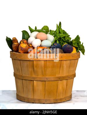 Korb mit Obst, Gemüse und Eiern aus der kalifornischen Sommerernte auf weißem Hintergrund, isoliert, auf Marmortisch, Seitenansicht, zentriert Stockfoto