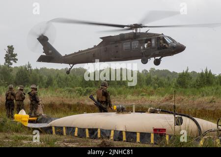 Marineinfanteristen, die der Marine Wing Support Squadron 273, Marine Air Control Group 28, MCAS Beaufort, South Carolina, zugewiesen sind, warten darauf, einen UH-60 Blackhawk mit Soldaten aufzutanken, die 4. Bataillon, 3. Aviation Regiment, 3. Combat Aviation Brigade, 3. Infantry Division in Fort Stewart, Georgia, 10. August 2022, zugewiesen wurden. Marineinfanteristen und Soldaten führten eine gemeinsame Aufrüst- und Auftankstelle durch, um die Fähigkeit zur Einrichtung und Aufrechterhaltung eines FARP zu steigern. (USA Armee-Foto von SPC. Caitlin Wilkins, 3. Combat Aviation Brigade) Stockfoto