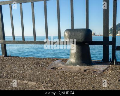 Schiffsparkplatz. Ein Poller zum Binden eines Schiffes. Platz zum Festmachen. Seeverkehr. Schwarzer Poller Stockfoto