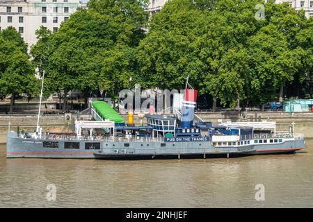 London, Großbritannien - 4. Juli 2022: Nahaufnahme des angedockten Tattershall Castle Pub-Bootes auf der Themse mit grünem Laub im Rücken. Stockfoto