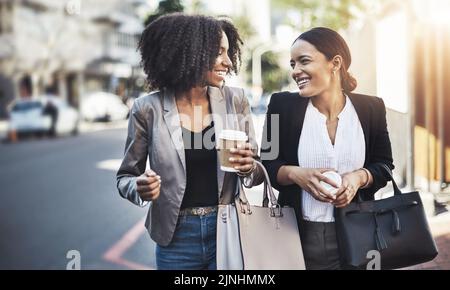 Mit absolutem Optimismus ins Büro. Zwei Geschäftsfrauen, die in der Stadt spazieren gehen. Stockfoto