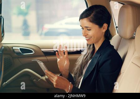 Der Empfang von guten Nachrichten am frühen Morgen ist beispiellos. Eine attraktive junge Geschäftsfrau, die während der Fahrt in einem Auto einen Videoanruf macht Stockfoto