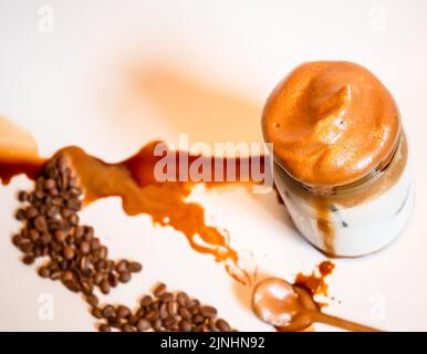 Chaotisch geschlagener Dalgona-Kaffee mit verschütteten Kaffeebohnen und Kaffee Stockfoto