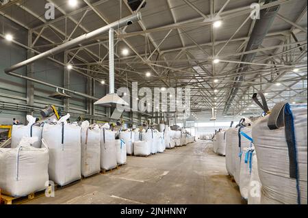 Riesige Plastiktüten mit Produkten auf Paletten in der Recyclingfabrik Stockfoto