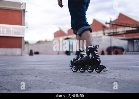 Rollschuhe Rollen im Park. Junge, der mit Rollschullaufbahnen auf einer Esplanade läuft. Schwarze Rollschuhe Rollen. Hochwertige Fotos Stockfoto