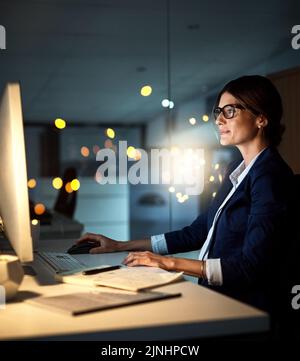 Shes wirklich für jede Aufgabe gewidmet. Eine junge Geschäftsfrau arbeitet spät an einem Computer in einem Büro. Stockfoto