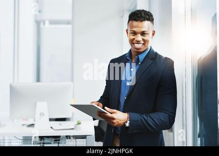 Technologie hält mich an der Spitze des Geschäftsspiels. Porträt eines jungen Geschäftsmannes, der im Büro ein digitales Tablet benutzt. Stockfoto