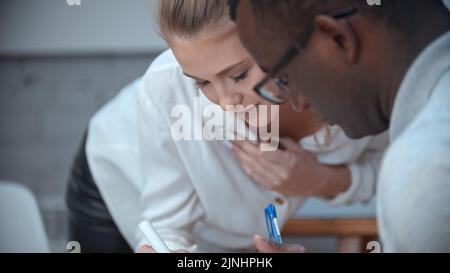 Eine Frau beugt sich vor ihrem schwarzen männlichen Kollegen Stockfoto