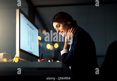 Shes widmet sich dem Job. Eine junge Geschäftsfrau arbeitet spät an einem Computer in einem Büro. Stockfoto