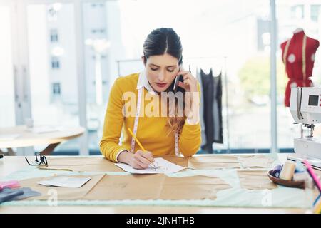 Ill maßgeschneidert auf Ihre Bedürfnisse. Eine attraktive junge Modedesignerin in ihrer Werkstatt. Stockfoto