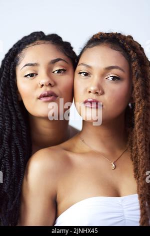 Natürlich schön. Studioaufnahme von zwei schönen jungen Frauen, die vor einem grauen Hintergrund posieren. Stockfoto