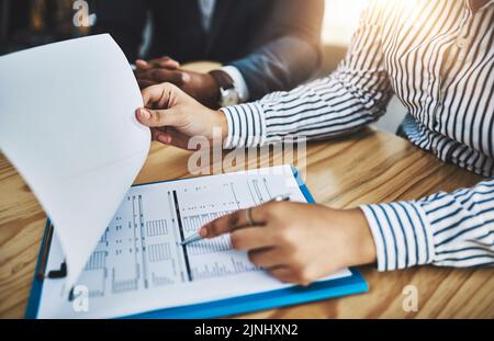Blättern durch einige wichtige Informationen. Nahaufnahme von zwei Geschäftsleuten, die in einem Büro Papierkram durchmachen. Stockfoto