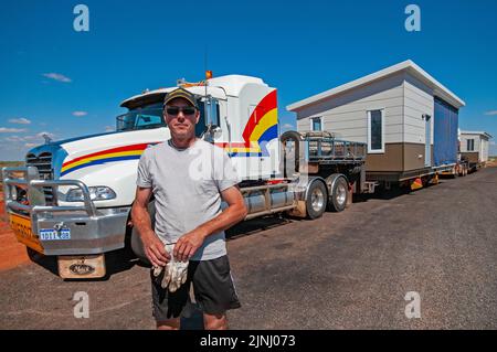 LKW-Fahrer im Transit, der vorgefertigte Gehäuse in zwei Abschnitten auf Lastwagen aus Perth transportiert, die in einer Bergbaustadt in der Nähe von Karratha in Westaustralien montiert werden sollen Stockfoto