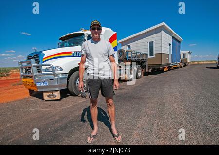 LKW-Fahrer im Transit, der vorgefertigte Gehäuse in zwei Abschnitten auf Lastwagen aus Perth transportiert, die in einer Bergbaustadt in der Nähe von Karratha in Westaustralien montiert werden sollen Stockfoto