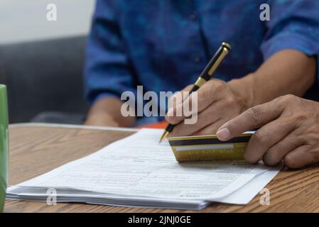Asiatische ältere Menschen sitzen und halten Kreditkarte und Stift für die Krankenversicherung Zahlung Finanzierung. Stockfoto